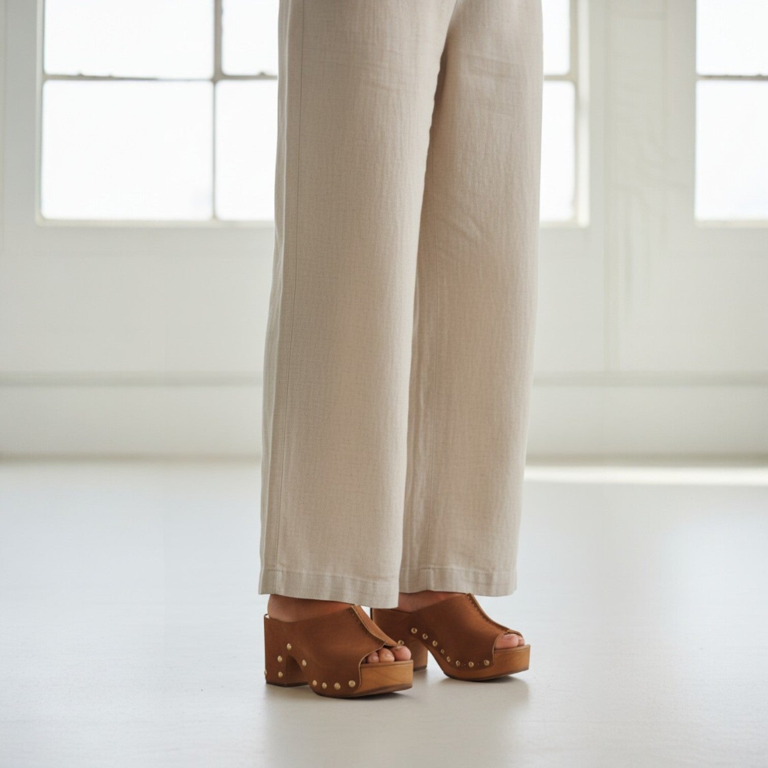 Zueco abierto de ante marrón de tretze-shoes con tacón ancho de plataforma de madera y tachuelas doradas.